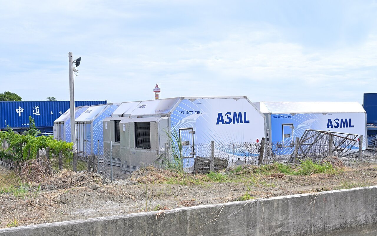 Conteneurs de transport aérien bleus et blancs marqués ASML, alignés sur un terrain en friche sous un ciel dégagé à Tainan, à Taïwan