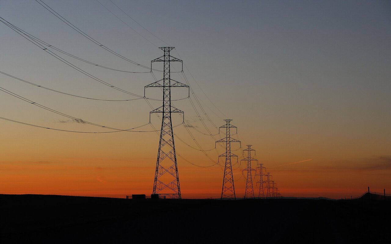 Lignes de transmission électrique haute tension sur pylônes lattice au coucher de soleil
