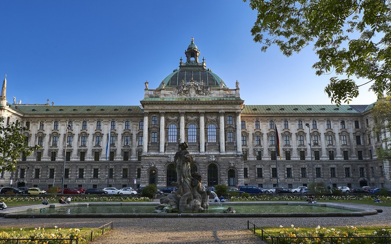 Façade du Palais de justice de Munich, grand bâtiment néobaroque surmonté d'une coupole, avec un bassin au premier plan