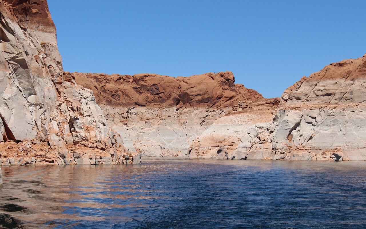 Falaises de grès du lac Powell marquées par une large bande claire au-dessus du niveau de l'eau, dans le canyon Navajo