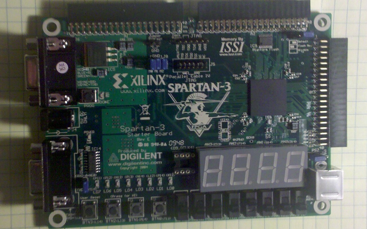 Carte de développement FPGA Xilinx posée sur une surface quadrillée, avec ses connecteurs, son afficheur à segments et sa puce centrale