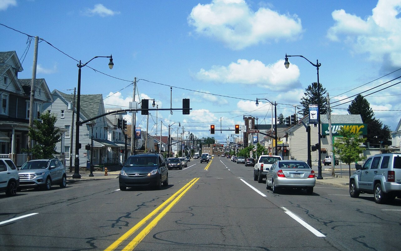 Rue résidentielle bordée de maisons individuelles et de voitures en stationnement à West Hazleton, en Pennsylvanie, sous un ciel nuageux