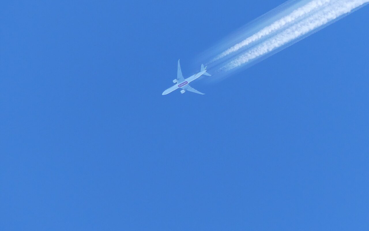 Traînée de condensation blanche créée par un avion en vol, vue de près contre le ciel bleu