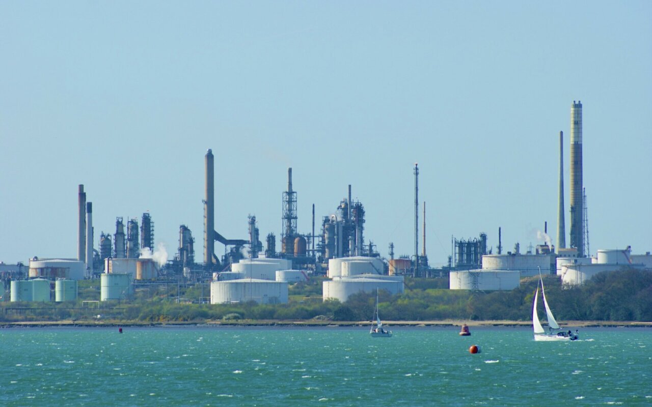 Vue d'une raffinerie de pétrole avec ses colonnes et ses réservoirs, photographiée depuis l'autre rive d'un estuaire