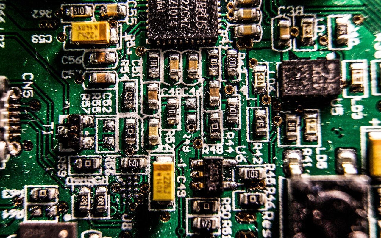 Gros plan d'un circuit imprimé montrant des composants électroniques, des pistes de cuivre et des connexions complexes