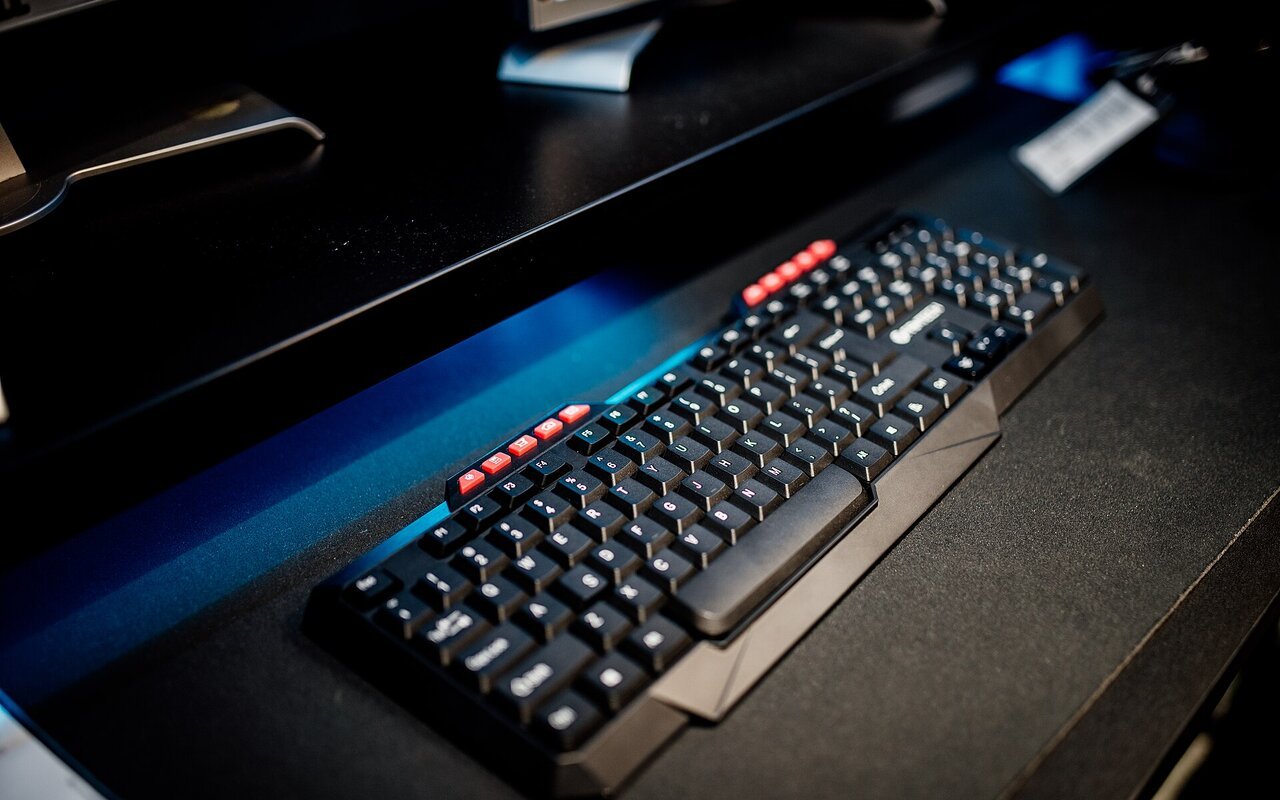 Clavier d'ordinateur sur bureau noir avec écrans en arrière-plan dans un bureau