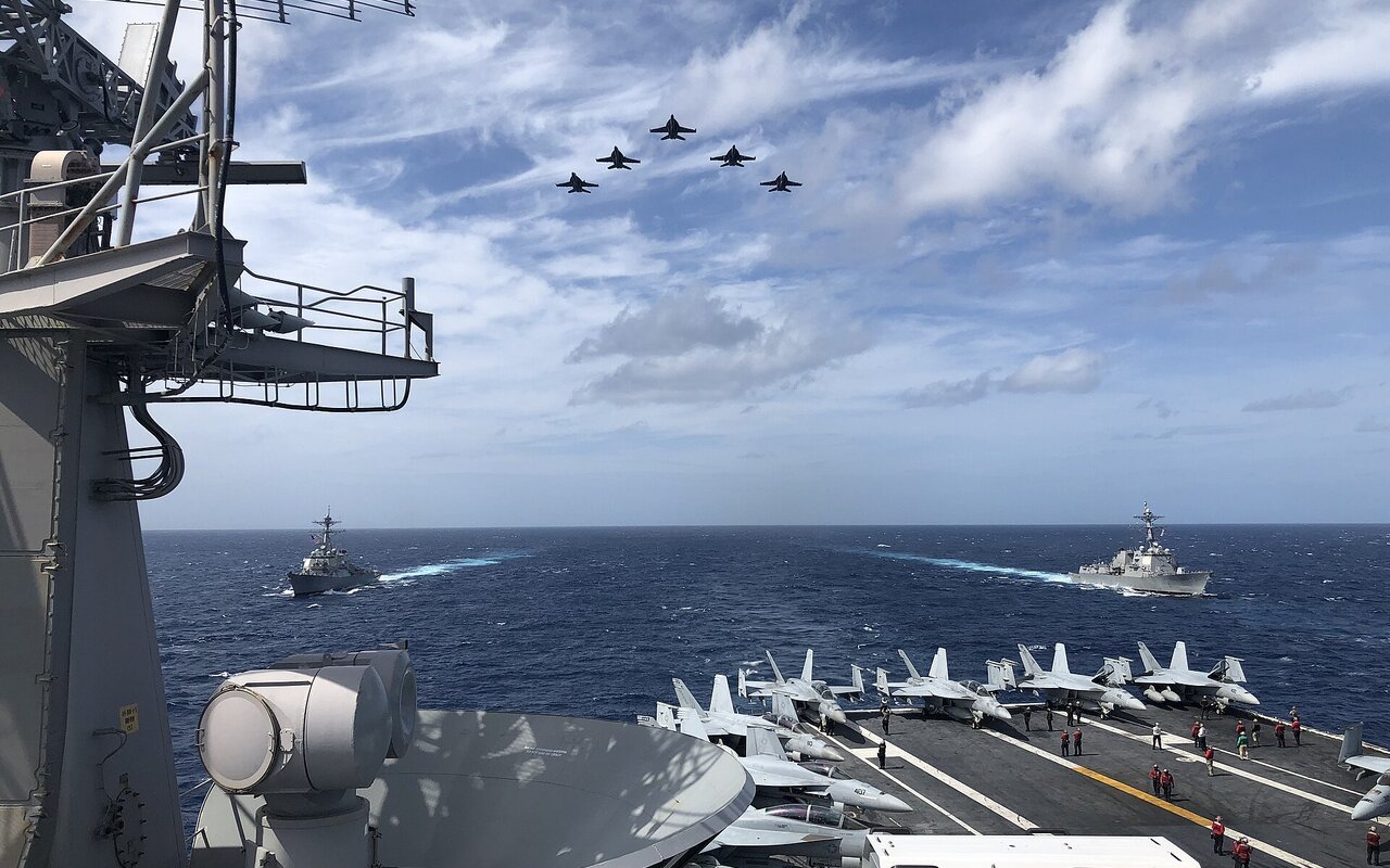 Avions de chasse en formation volant au-dessus de navires militaires en mer