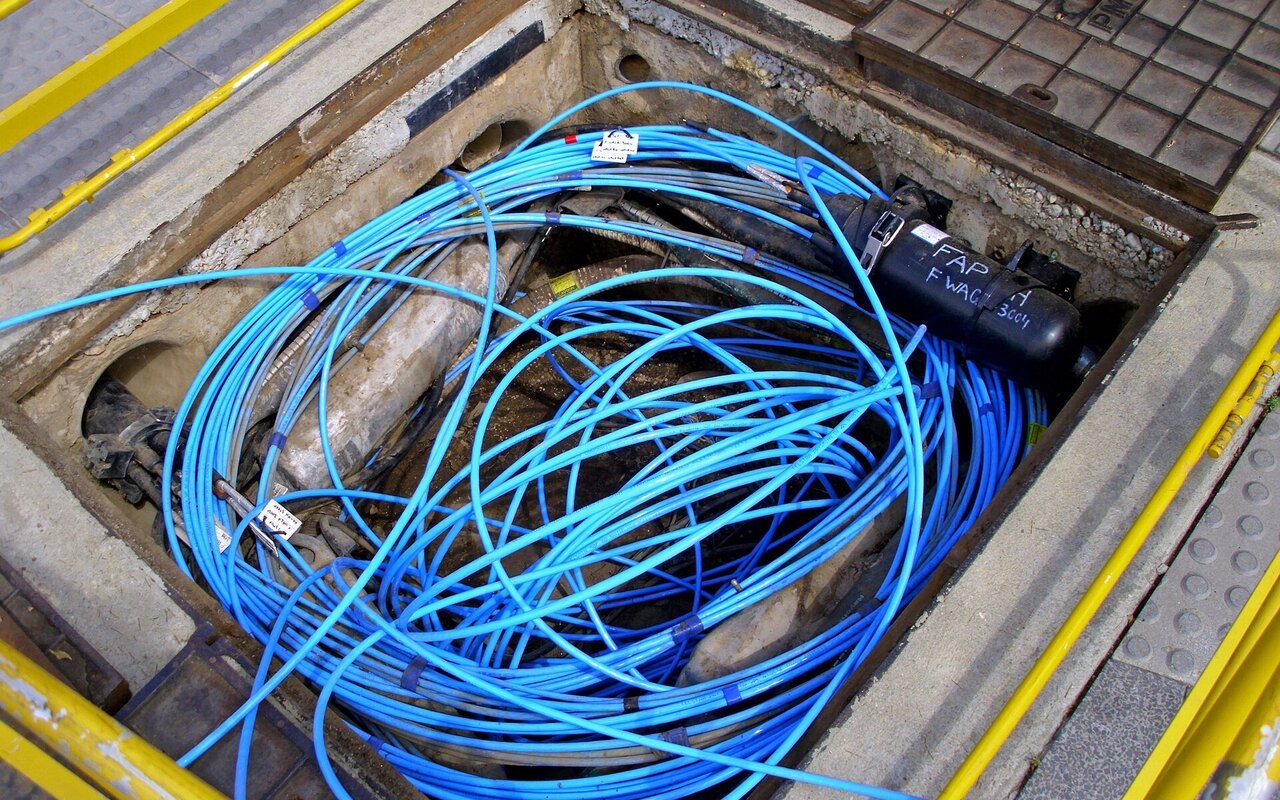 Câbles fibre optique et deux épisseurs de fibre dans une fosse de câbles Telstra.