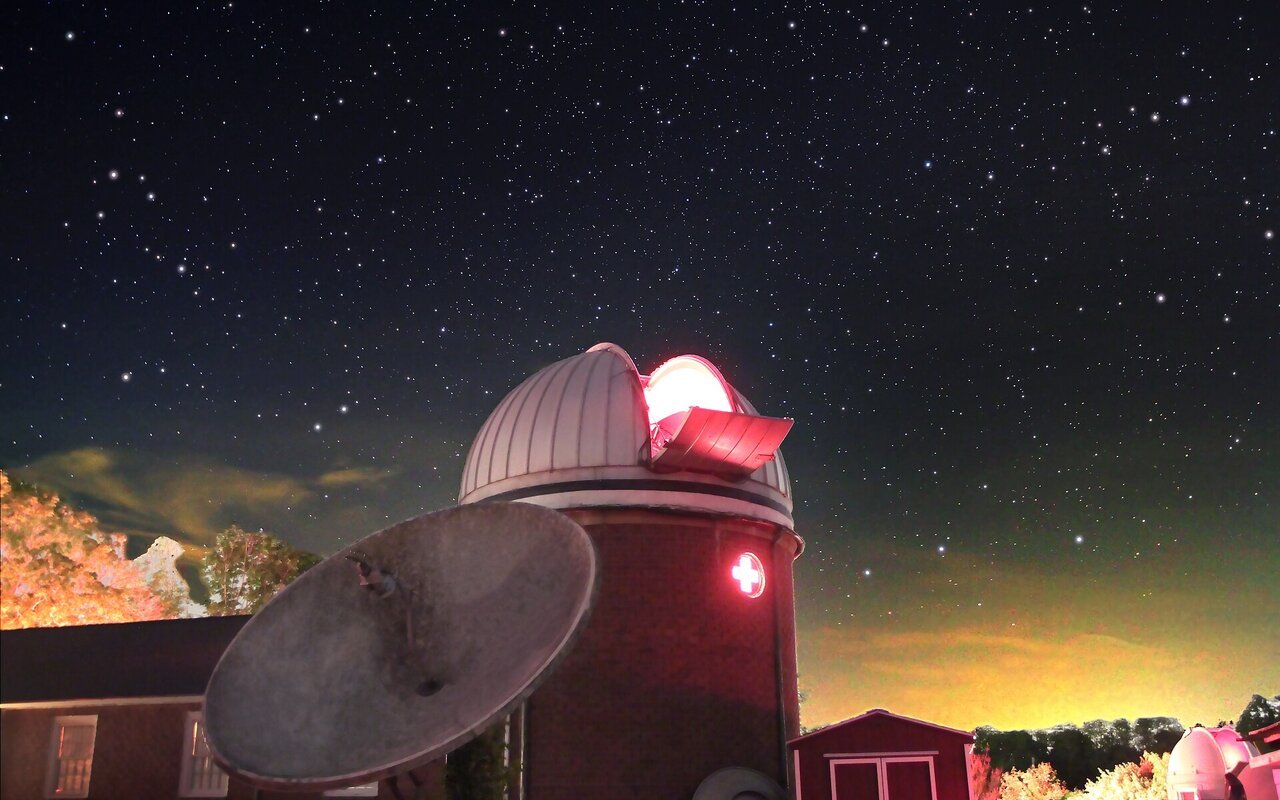 Observatoire astronomique avec dôme blanc et radiotélescope sous un ciel étoilé nocturne