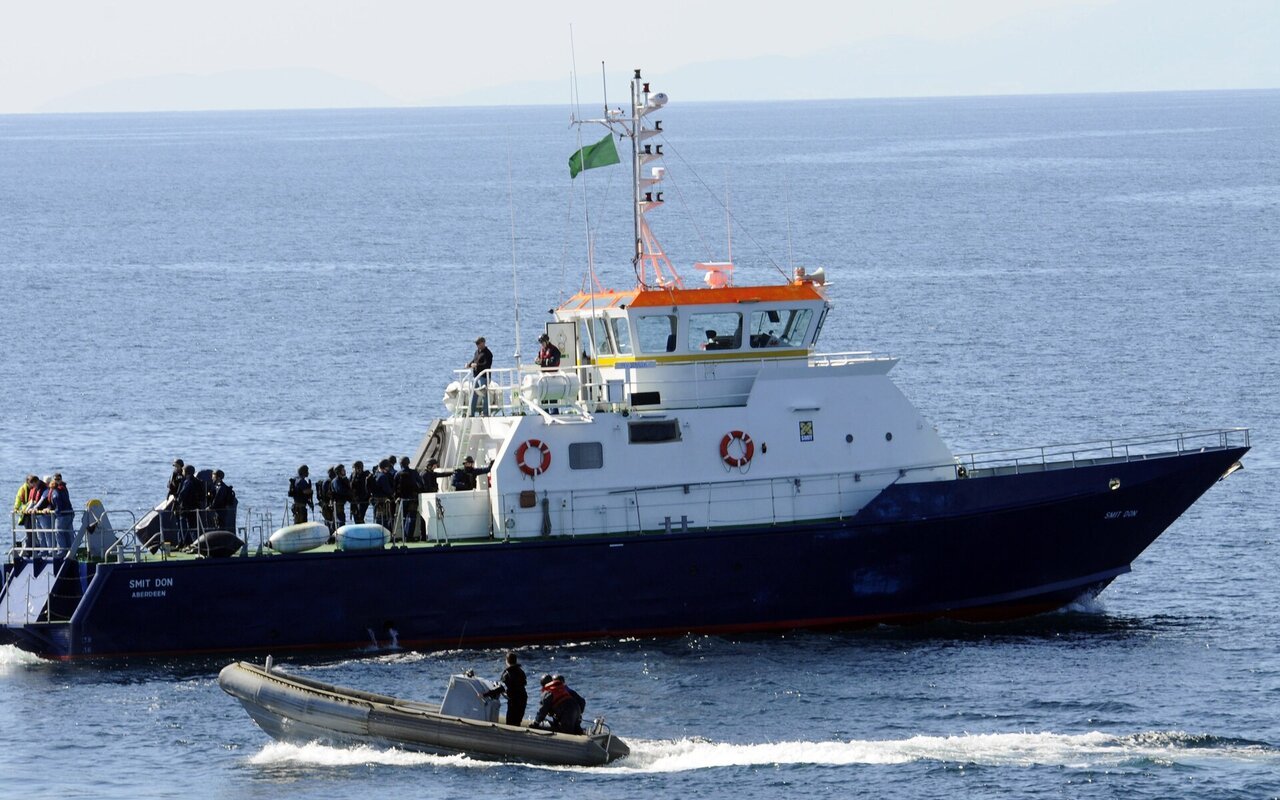 Une embarcation semi-rigide de l'US Navy transportant une équipe de visite s'approche en pleine mer d'un navire civil à coque bleue
