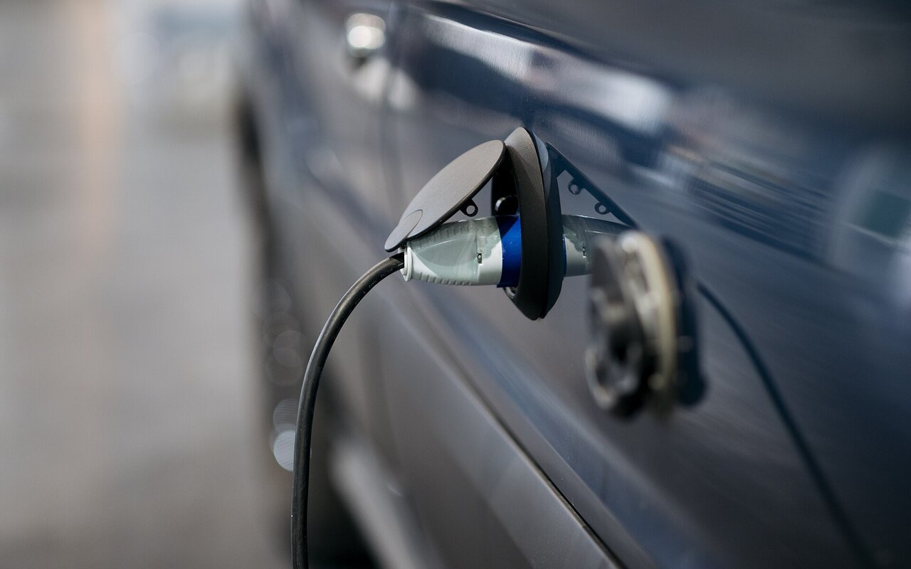 Voiture électrique bleue branchée à une station de recharge en milieu urbain