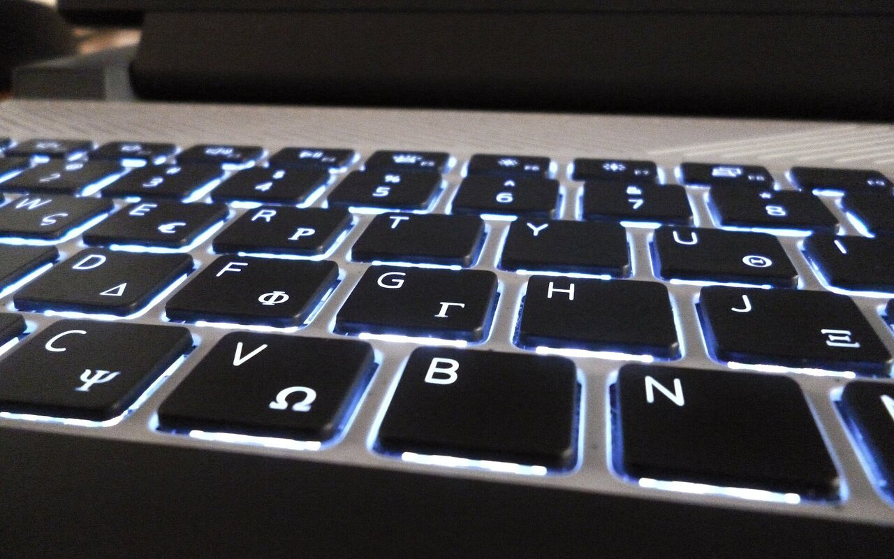 Clavier d'ordinateur portable rétroéclairé avec touches illuminées en bleu, photographié en contre-jour