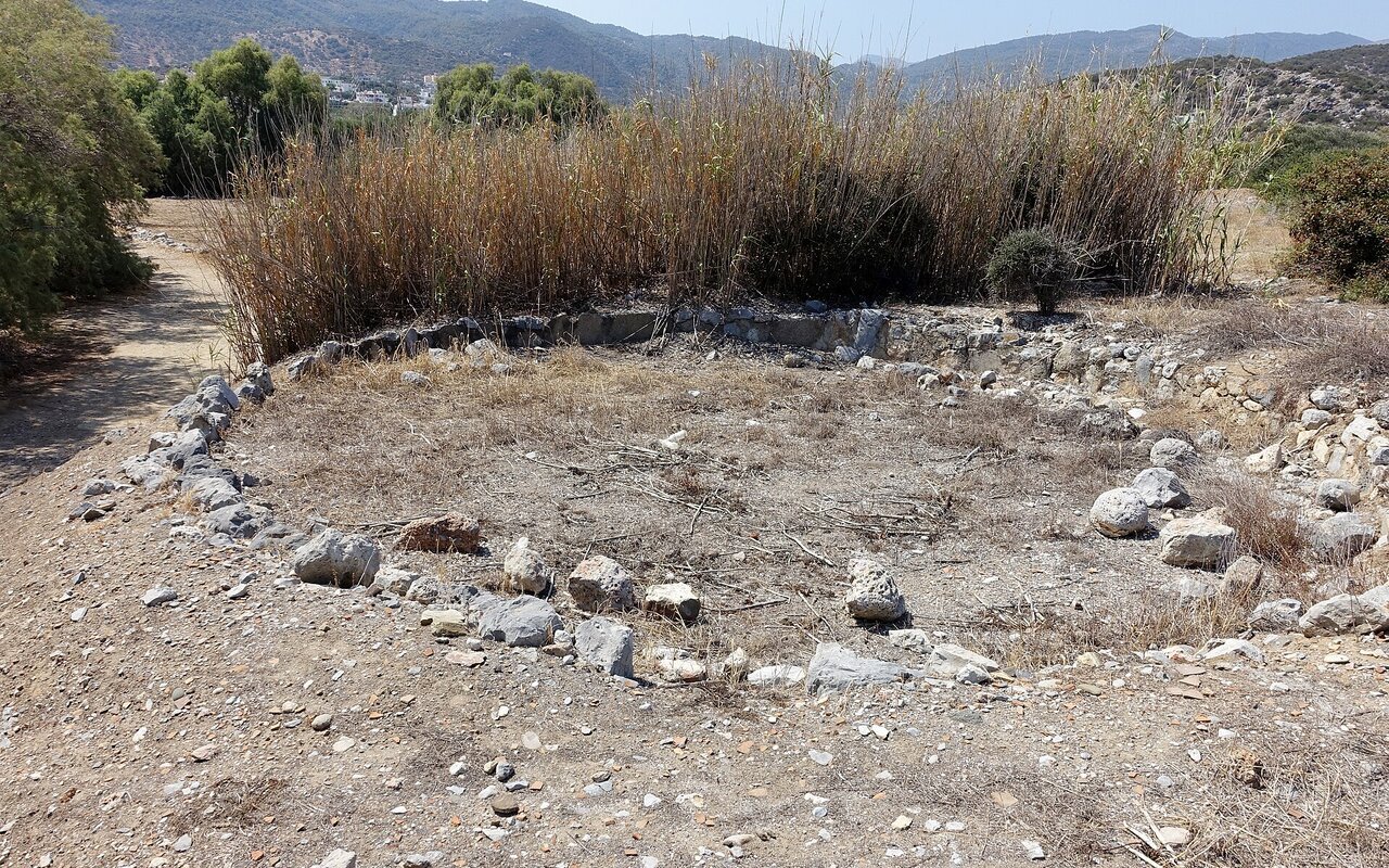 Site archéologique avec structures de pierre excavées et murs partiellement dégagés