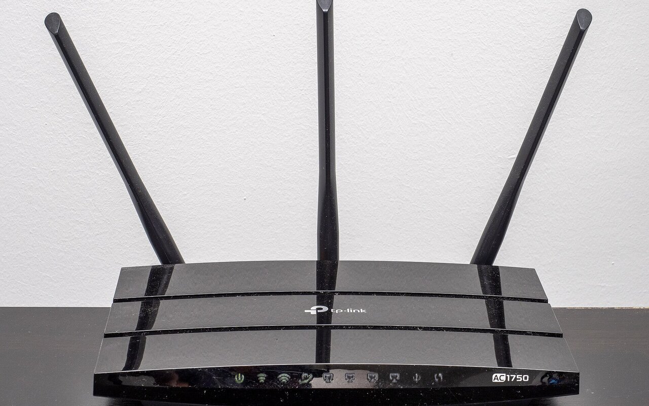 Routeur Wi-Fi TP-Link noir posé sur une table, doté de trois antennes externes dressées, avec le logo de la marque et la référence du modèle sur la façade