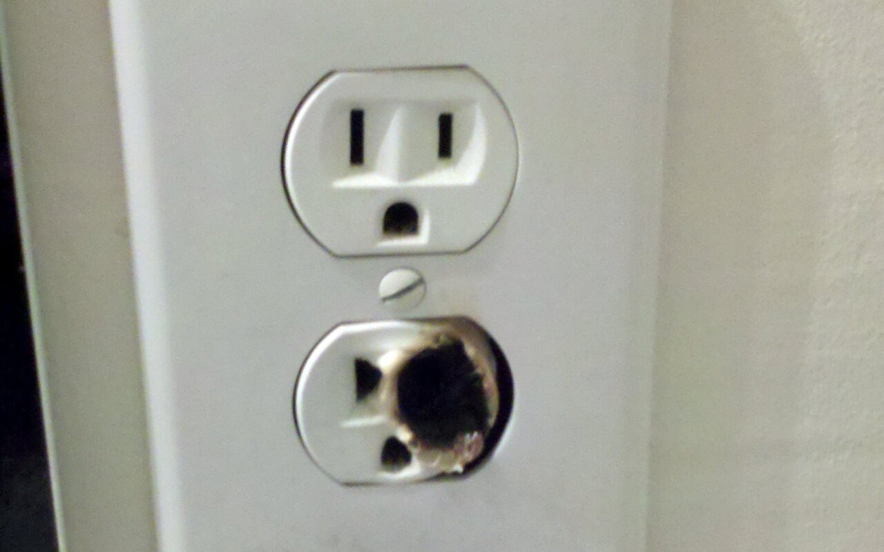 Prise électrique murale noircie par une surchauffe