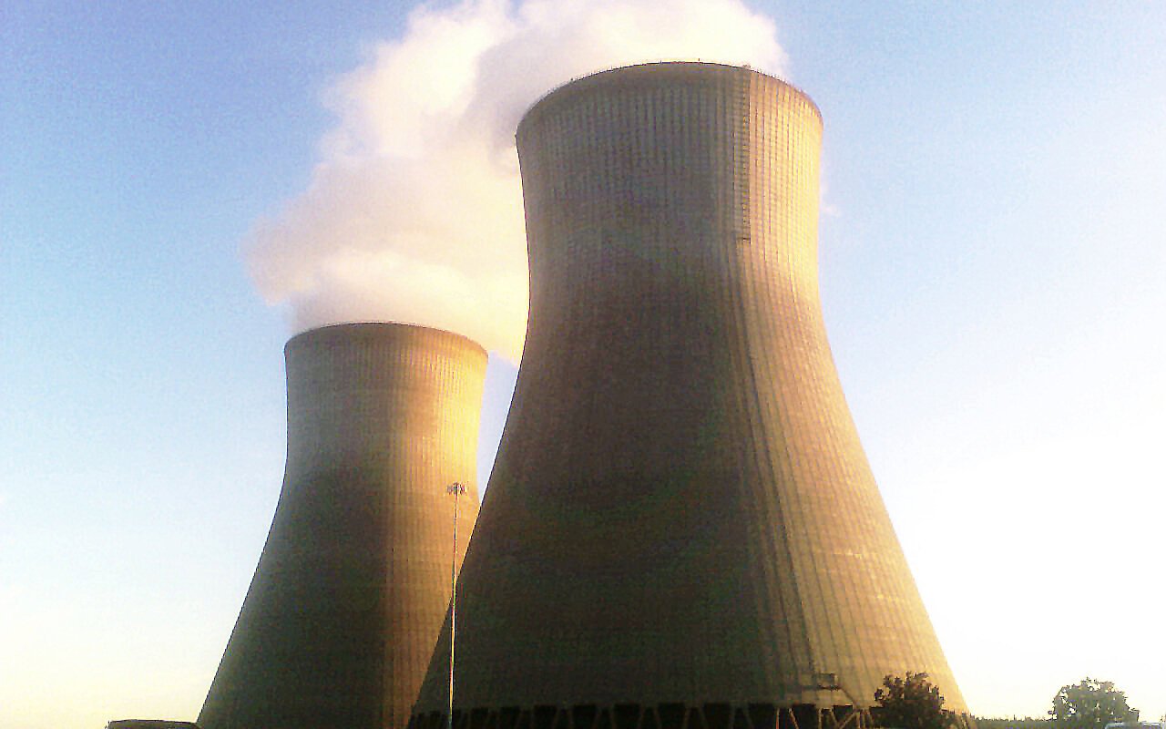 Deux tours de refroidissement d'une centrale nucléaire rejetant un panache de vapeur au crépuscule