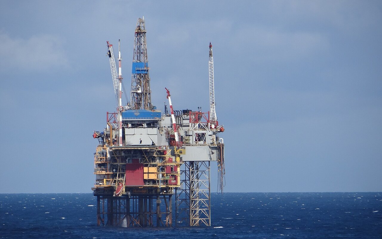 Plateforme offshore fixe posée sur ses pieds métalliques en mer du Nord, surmontée d'un derrick, sous un ciel clair