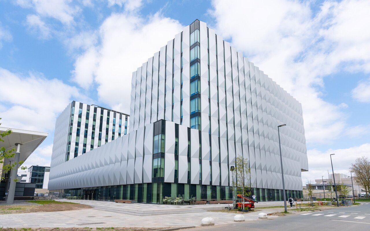 Bâtiment de bureaux moderne d'ASML, façade blanche et vitrée, sur le site de Veldhoven aux Pays-Bas, sous un ciel bleu