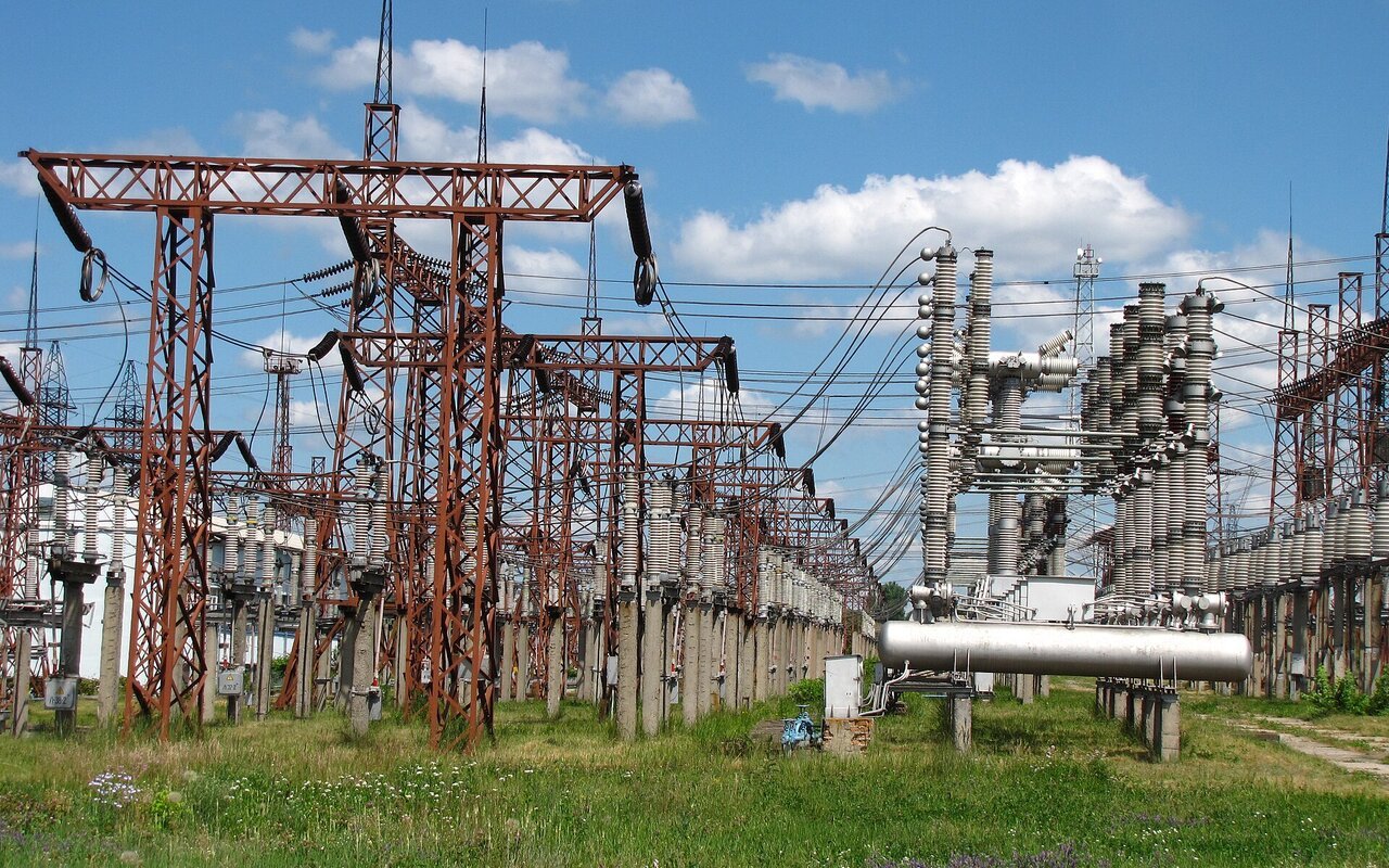 Portiques et appareillage haute tension d'un poste électrique sous un ciel bleu
