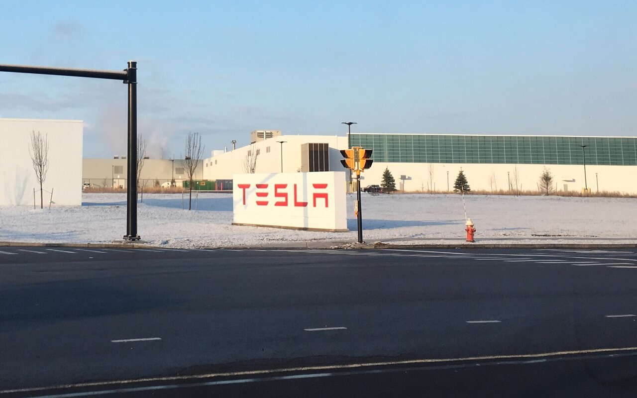 Panneau rouge Tesla devant le bâtiment de l'usine Gigafactory 2, à Buffalo, dans l'État de New York, au bord d'une route enneigée
