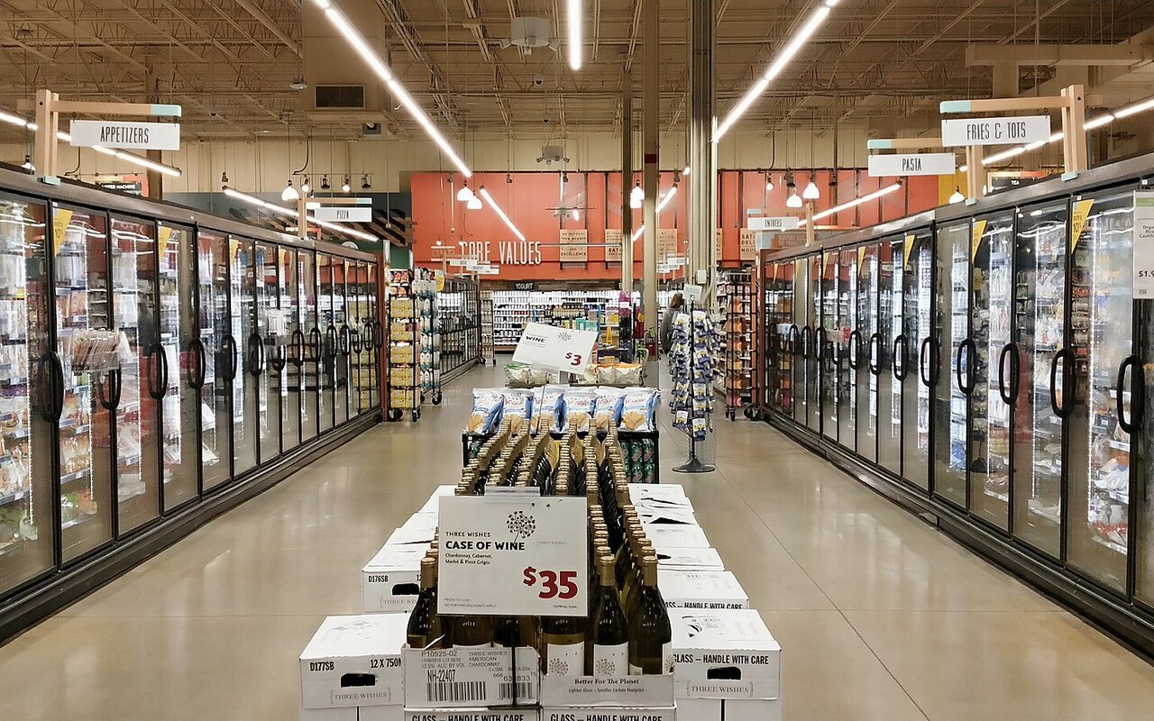 Allée de surgelés d'un supermarché bordée de part et d'autre d'armoires réfrigérées à portes vitrées éclairées.