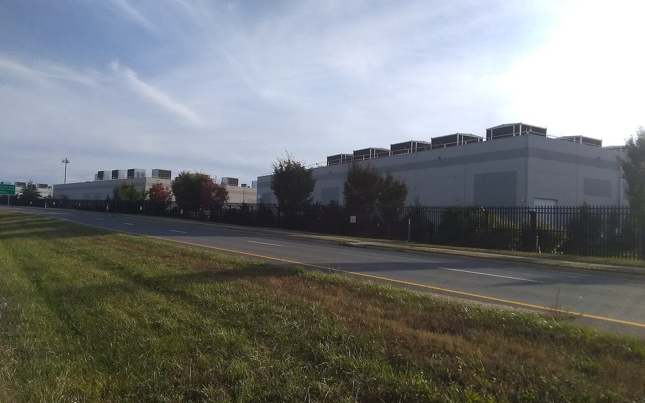 Bâtiment bas et sans fenêtres d'un centre de données bordé d'une pelouse et d'une route, à Ashburn en Virginie