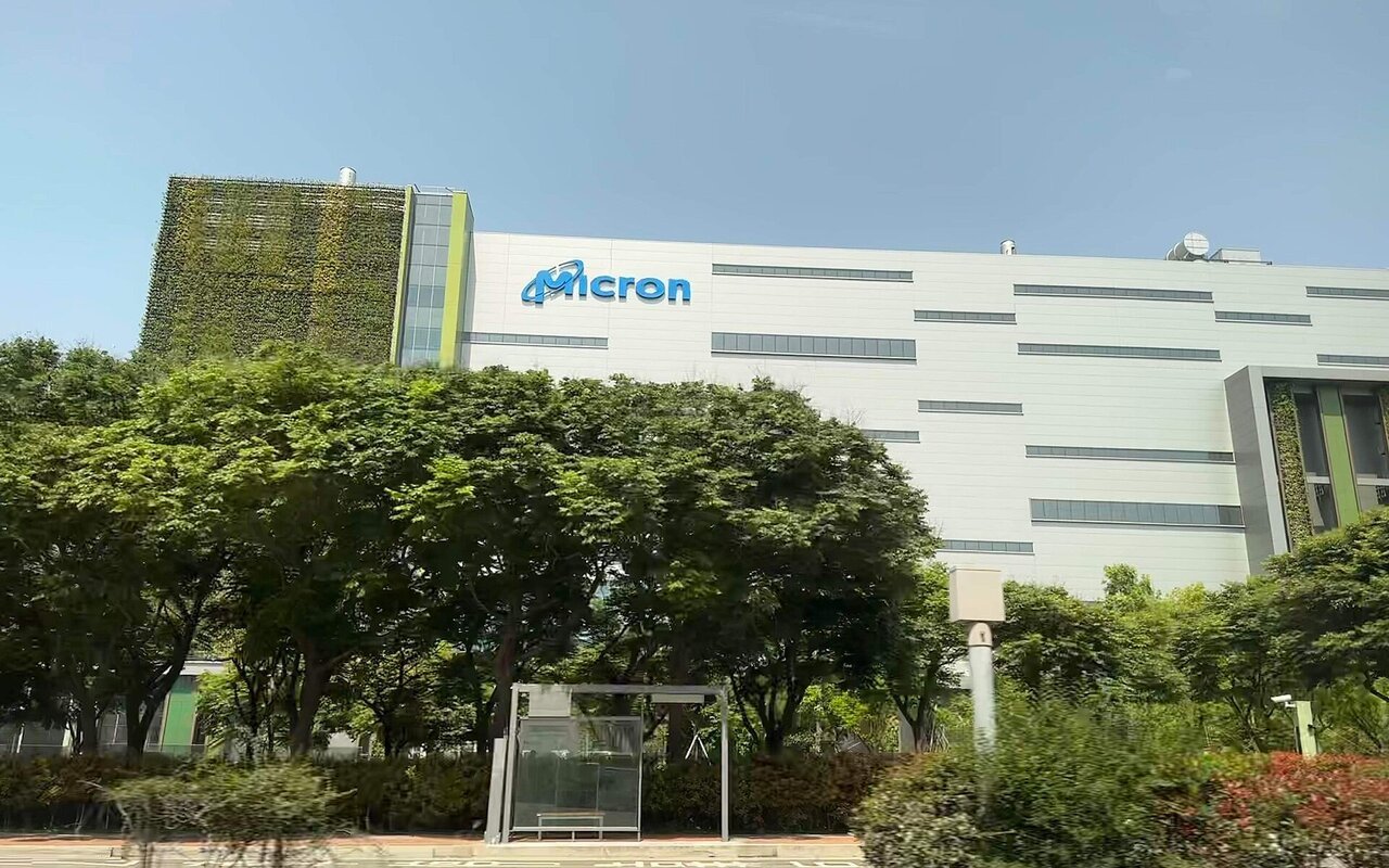 Le bâtiment de l'usine Micron de Taichung, à Taïwan, avec le logo Micron sur la façade, vu depuis la rue derrière des arbres